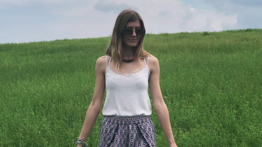 Cute young woman jumping in a green field.
