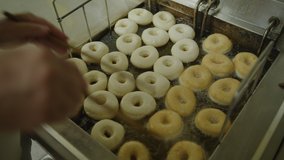 Baker flipping donuts floating in bubbling hot oil in fryer / Pleasant Grove, Utah, United States - Powered by Shutterstock - Get 15% off with code: PIKWIZARD15