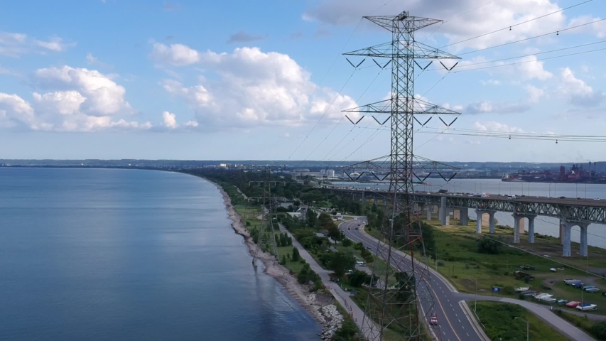Aerial view of Burlington Bay James N. Allan Skyway arch bridge, power lines along QEW highway and Hamlton harbour. Shot with drone. Sunny summer day. Hamilton Bay waterfront, Ontario, Canada.