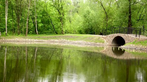 Beautiful pedestrian stone bridge over the river in the park