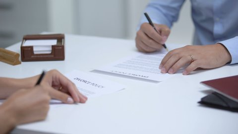 Couple signing divorce policy, woman removing ring, man trying to save relations