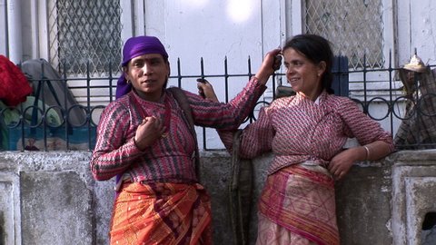 Calcutta / India - 08 09 2019: Two Indian women standing with one another chatting and smiling, they are relaxed, learning on a wall and holding onto a railing.
