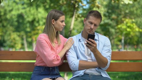 Girl trying to attract attention of boyfriend playing on phone and ignoring she