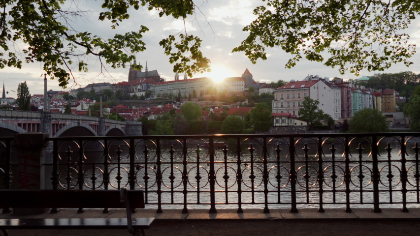 beautiful view from embankment of Vltava river at sunset in roofs of houses. Sweet girl comes up to fence to look at this picturesque view, Prague, Czech Republic