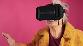 very old grandma , dressed fashionably and youth takes off his glasses virtual reality . VR glasses. isolated, pink background.