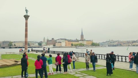 Stockholm , Stockholm / Sweden - 06 11 2018: Asian tourists gathering at small park between the Stockholm city hall and lake Mälaren's shore Slow motion