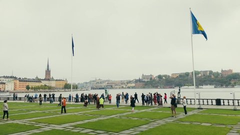 Stockholm , Stockholm / Sweden - 06 11 2018: Long shot of tourists gathering at lake mälaren water front behind Stockholm city hall Slow motion