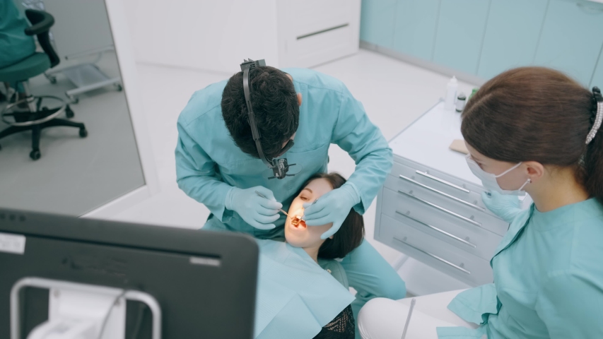 Dentist with nurse and patient in dentist office. A patient getting dental treatment at dental office, Dentist and assistant during teamwork | Shutterstock HD Video #1036608974