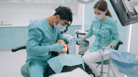 Dentist with nurse and patient in dentist office. A patient getting dental treatment at dental office, Dentist and assistant during teamwork