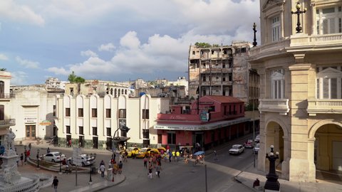 Havana / Cuba - 06 15 2019: A static medium shot of a busy street outside the famous bar, La Florida, Cuba, the home of daiquiri. Pedestrians cross the street in front of yellow taxis, classic cars, a