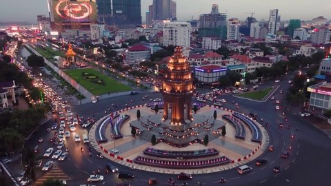 Phnom Penh / Cambodia - 07 14 2019: aerial evening view of the busy roundabout of Independence monument with beautiful illumination and Independence park right behind it
