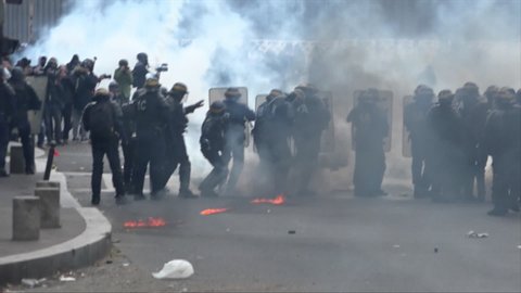Paris / France - 08 17 2019: Riot police surrounded by tear gas and fire