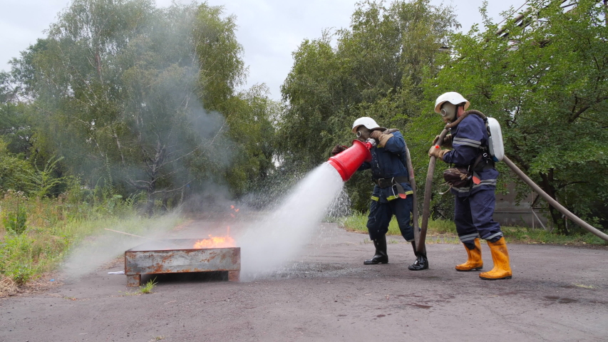 Teachings. Two firefighter push fire with foam