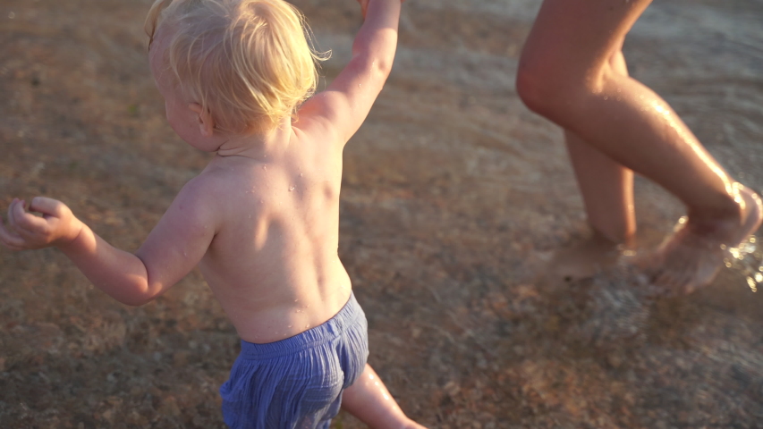 Child girl in swimming shorts standing near mother