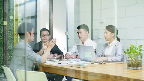 group of young asian entrepreneurs discussing business in company meeting room