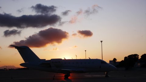 Timelapse of clouds running over a parked private jet aircraft on a nice summer sunset.