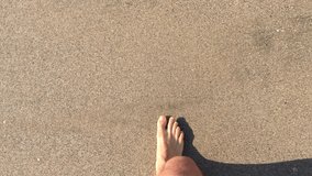 4k video Man feet walking on the shore with very calm waves crushing or splashing on sandy beach. Top view
