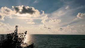 4k video  Relaxing calm sea or ocean with big clouds birds and left side tree and small gust of wind