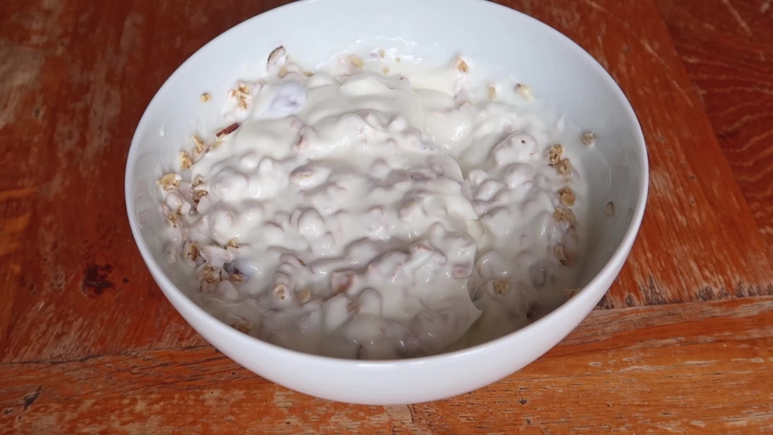 Granola grains being poured into a bowl of yoghurt Royalty-Free Stock Footage #1036641059