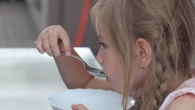 Child Eating Milk and Cereals at Breakfast in Kitchen, Girl Tasting Meal 