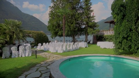 Luxury wedding in Switzerland. Beautiful outdoor banquet room. Romantic dinner. Wedding table, festive hall of the restaurant, decorated with chandeliers, bright colors and curtains. Floristry on Lake