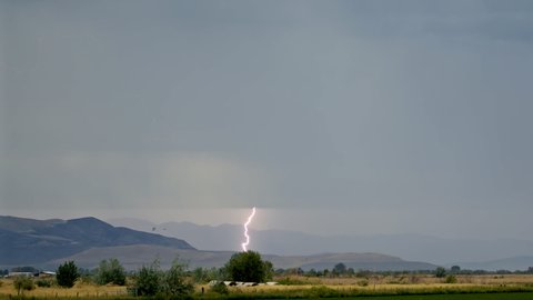 Lightning bolt flashing in the sky contacting the ground as it flashes as rainstorm moves through Utah Valley.