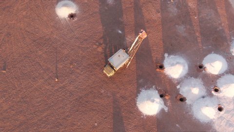 Aerial: Opal vacuum mine truck in working mine in the outback region of Coober Pedy at sunrise. Heaps of mining sand visible in piles from exhausted holes. Australia