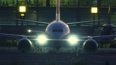Airplane taxiing on the airfield at the airport terminal before taking off at night