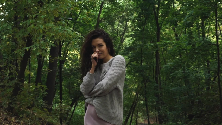 Beautiful curly girl poses and walks in the forest. She smiled sweetly and has braces on her teeth.