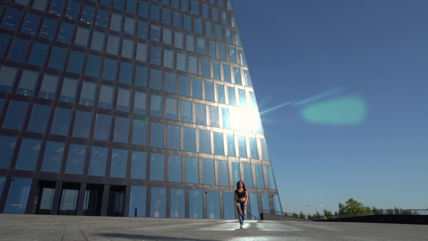 Cool girl dancing on the background of a modern building. Sunny summer day in Moscow.	