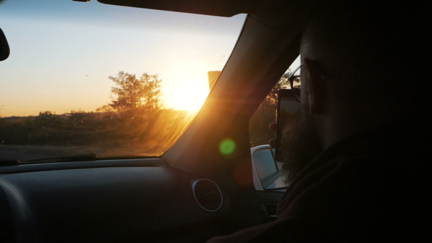 Young bearded man traveling in the car looking outside the window at sunset | Shutterstock HD Video #1036672136