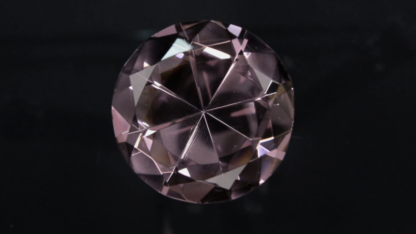 Rotation of a large pink rhinestone on a black background. With space for design, text place.