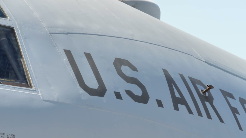 A big US Airforce tag on the side of the white airplane parking on the airport runway area