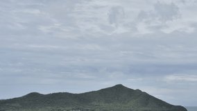 4K time lapse cloudy blue sky over the ocean and mountain with panning right. 