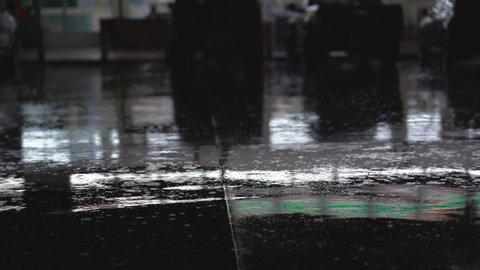 Raining on ground on night on blurred car and market store