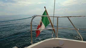 4K video of Italian flag fluttering in the wind. The flag is on a yacht that goes on the sea off the island of Sardinia.