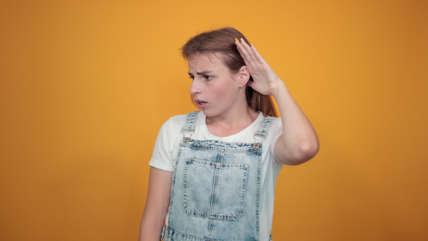 Young woman wearing white t-shirt, over orange background shows emotions