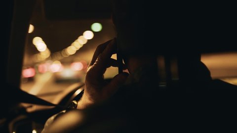 A man talking on the phone behind the wheel. He's going through a tunnel. Close - up from the back seat.