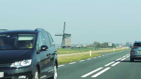 Netherlands - Circa 2019: Rear view of new Hyundai Kona SUV driving fast on Dutch highway early in the morning with traditional wind mill in the background