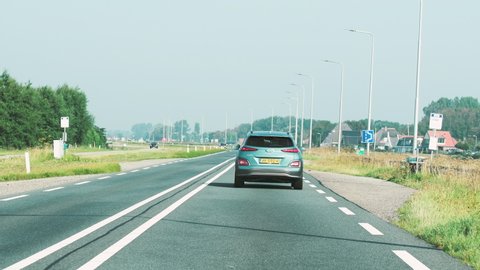 Netherlands - Circa 2019: Rear view of new Hyundai Kona SUV driving fast on Dutch highway early in the morning with beautiful houses in background
