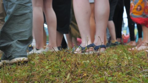 The audience is dancing at an open-air concert. Close view of the legs.