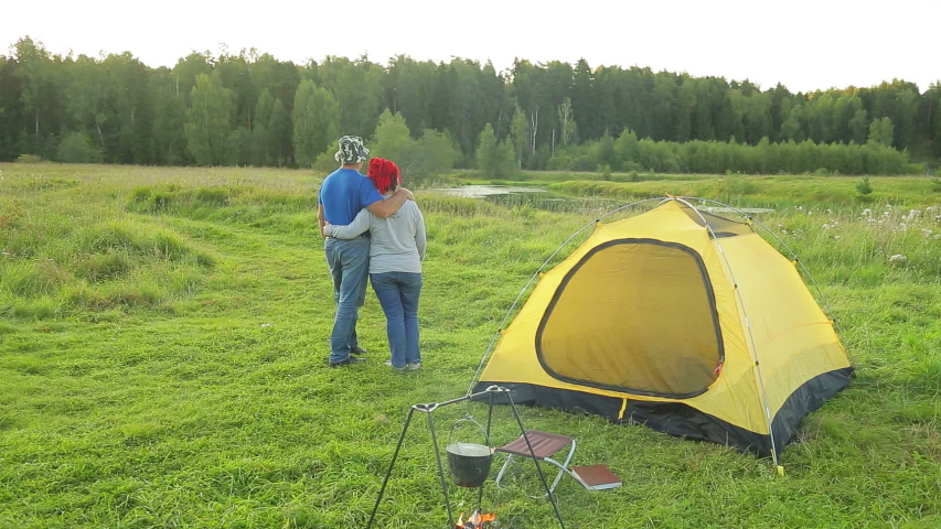 A man and a woman near the tent hugging admiring nature