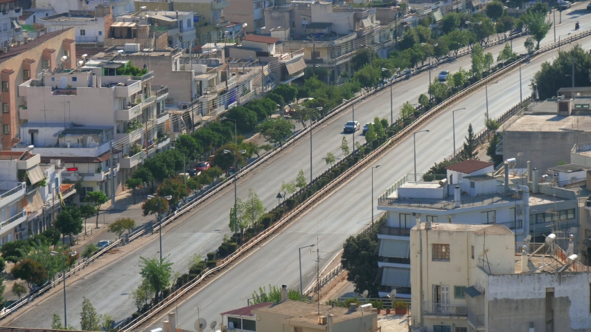 Splendid view of Athens roads with busy traffic and high residential and administrative houses  with trees around them on a sunny day in summer