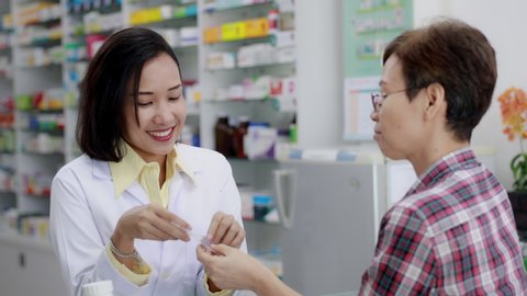 footage pharmacist talking with female patients regarding the details of purchased drugs in pharmacy store Thailand business health care concept