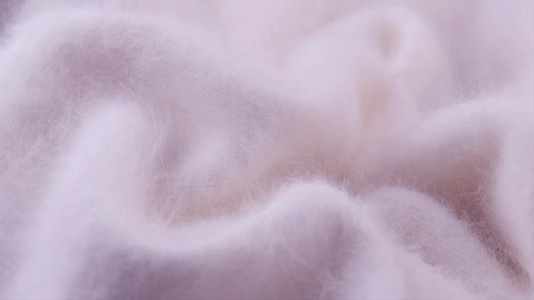 Soft Wool background. Alpaca wool mohair clothes texture closeup. Natural Cashmere Soft and fluffy merino wool macro shot. Woolen fabric. Knitted hairy detail texture surface Rotated. 4K UHD slowmo.