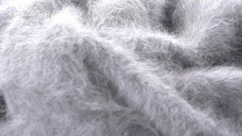 Wool background. Alpaca wool mohair clothes texture closeup. Cashmere Soft and fluffy grey merino wool macro shot. Woolen fabric. Knitted texture surface Rotated. Slow motion. 4K UHD video.