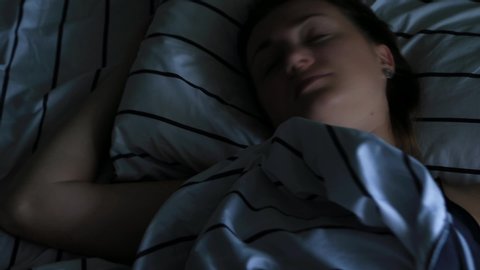 Woman has insomnia, tosses and turns in bed