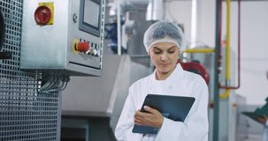 Closeup taking video in the manufacturing industry engineer woman good looking take some notes in her electronic tablet and checking the industrial machine