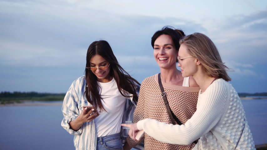 Beautiful women looking at pictures on the phone while walking.
