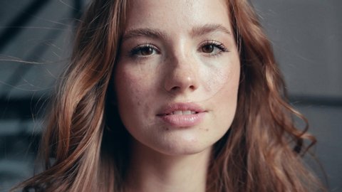 Close-up portrait of happy beautiful young woman with golden hair and freckles looking at camera feel happy the light wind blows